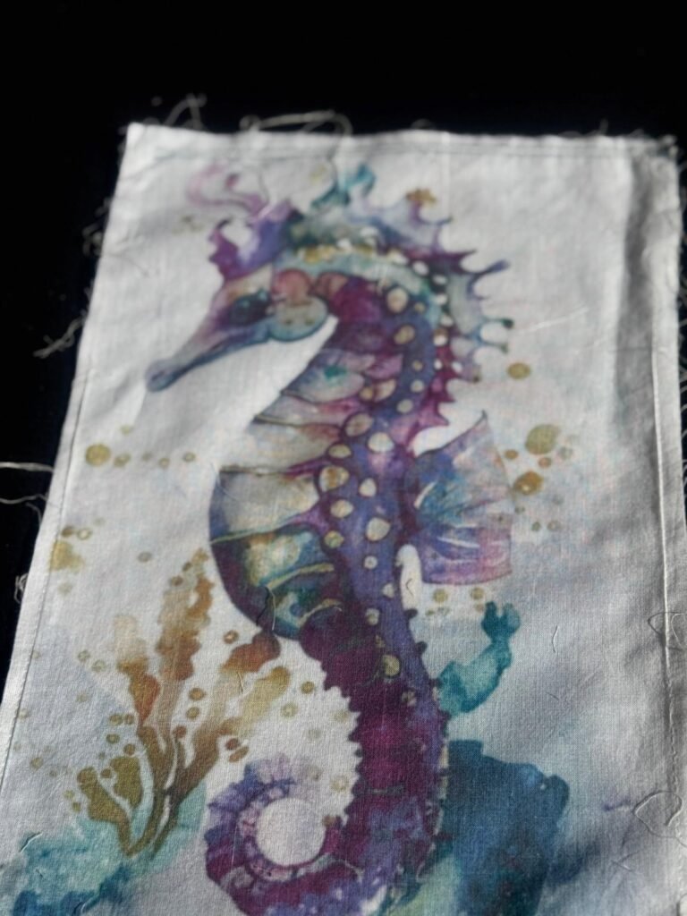 This is a piece of textile art featuring a colorful watercolor seahorse illustration. embroidered patch or appliqué