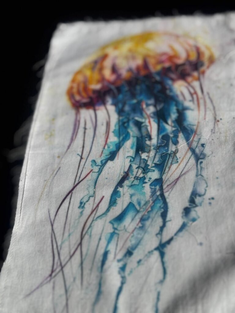 The image is a watercolor painting of a jellyfish on paper or fabric. embroidered patch or appliqué